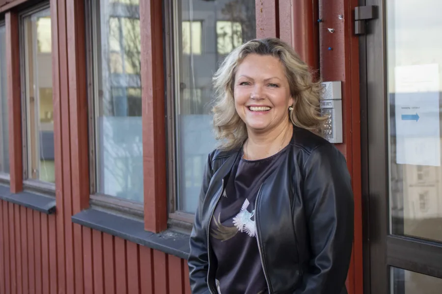 En person som smiler foran en rød dør