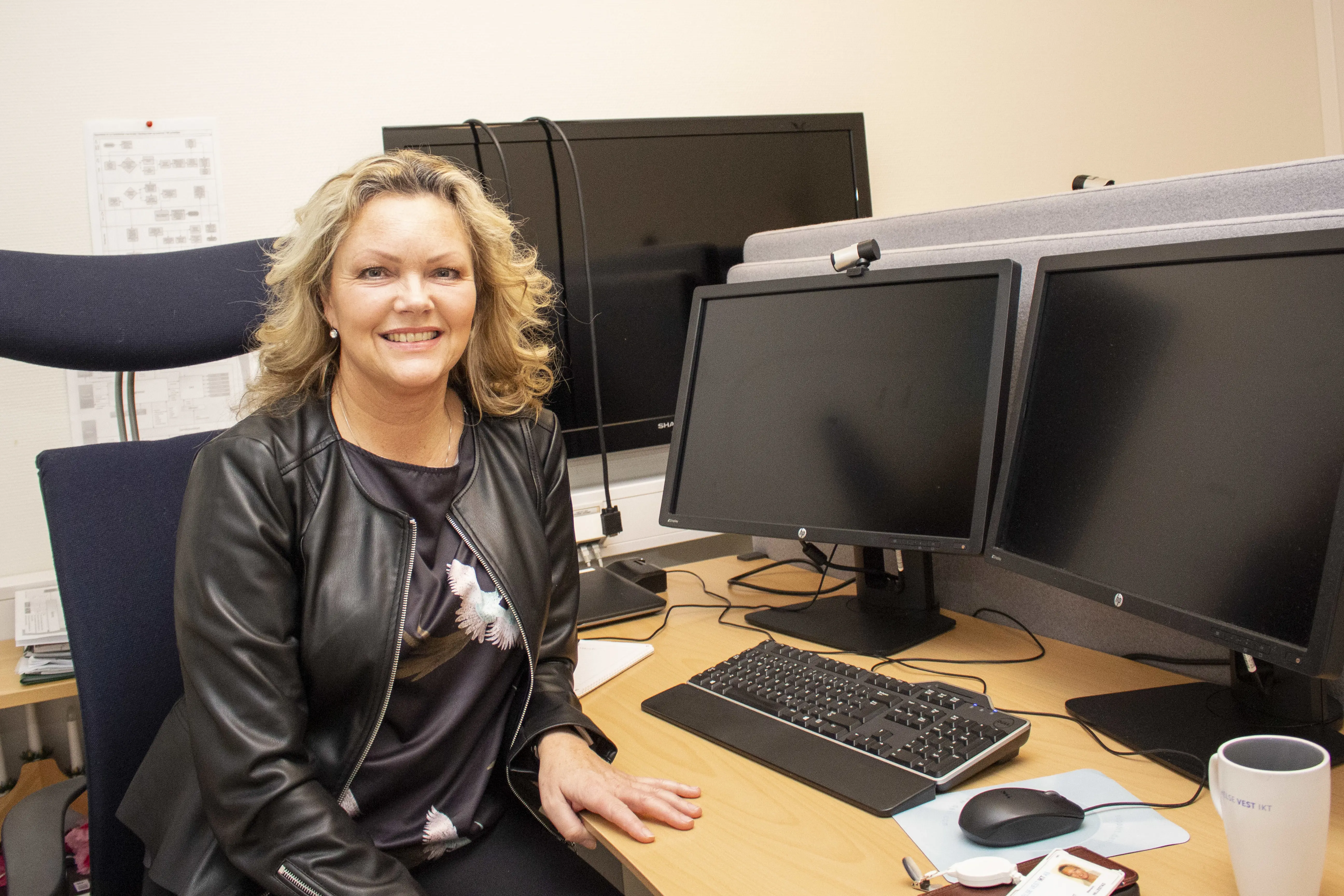 En person som sitter ved et skrivebord med en datamaskin og et tastatur