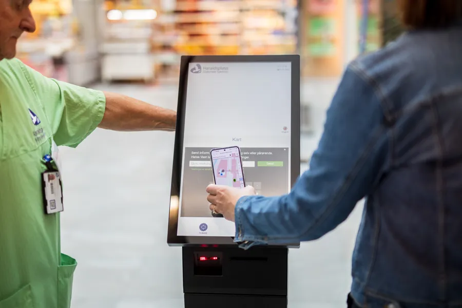 Kvinne holder mobil over skjerm