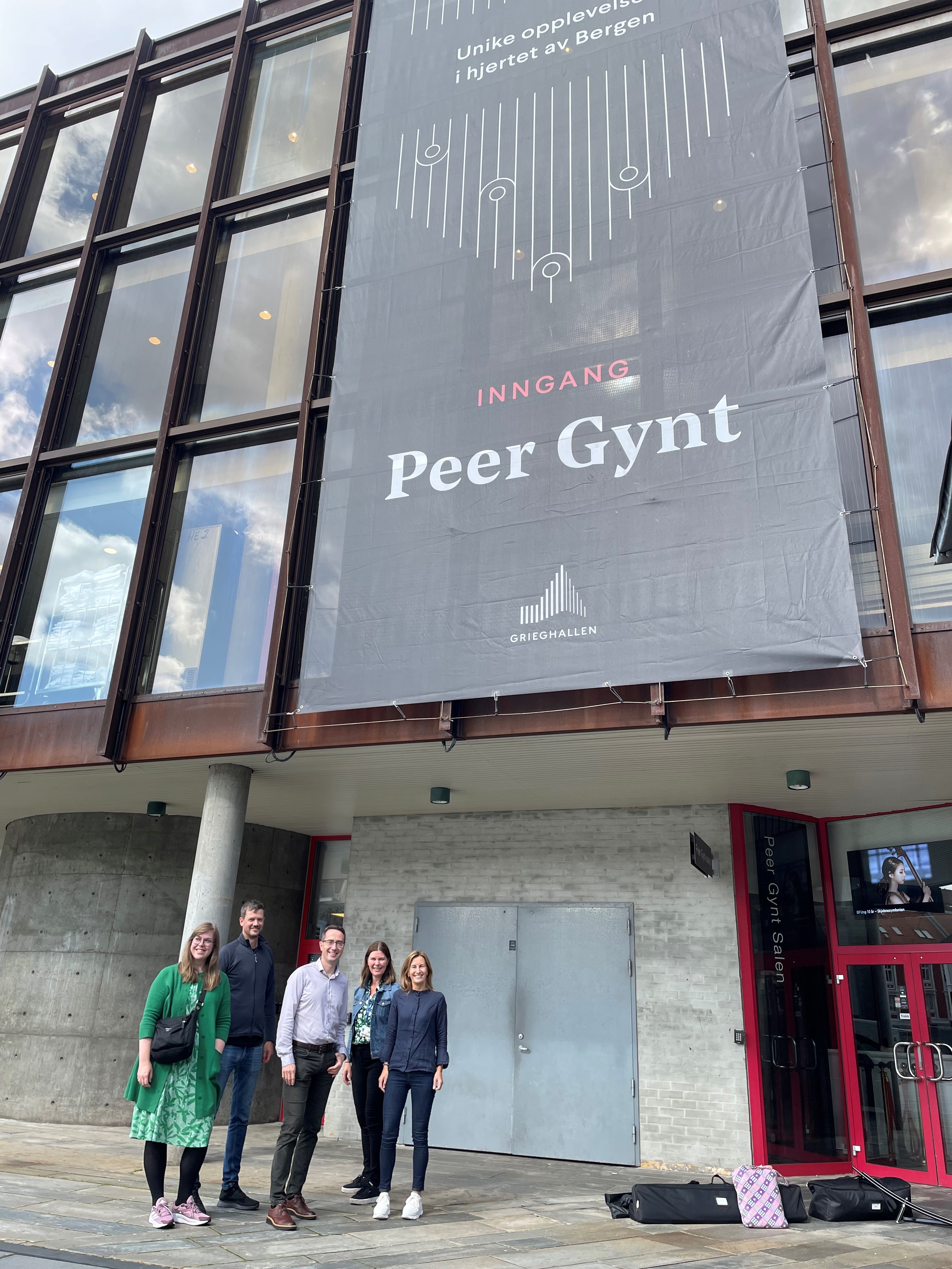 En gruppe mennesker som står foran et skilt