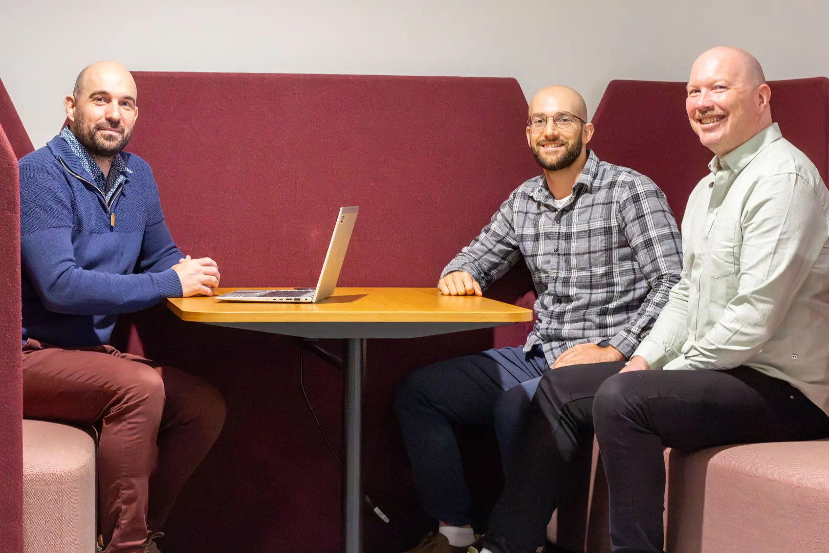 En gruppe menn som sitter ved et bord med en bærbar datamaskin