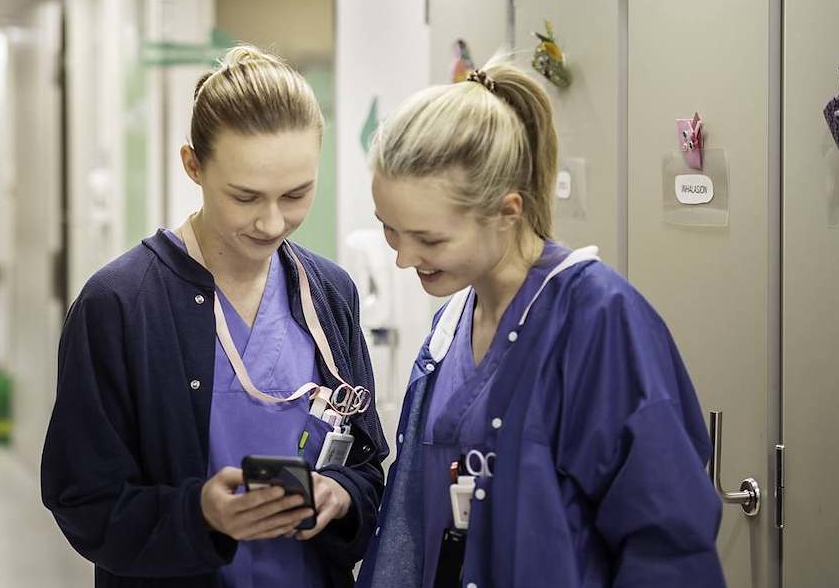 Kvinner i arbeidsklær som ser på en telefon