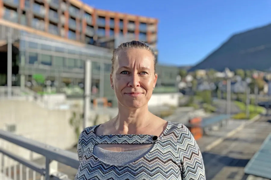 Dame foran bygning og gjerde