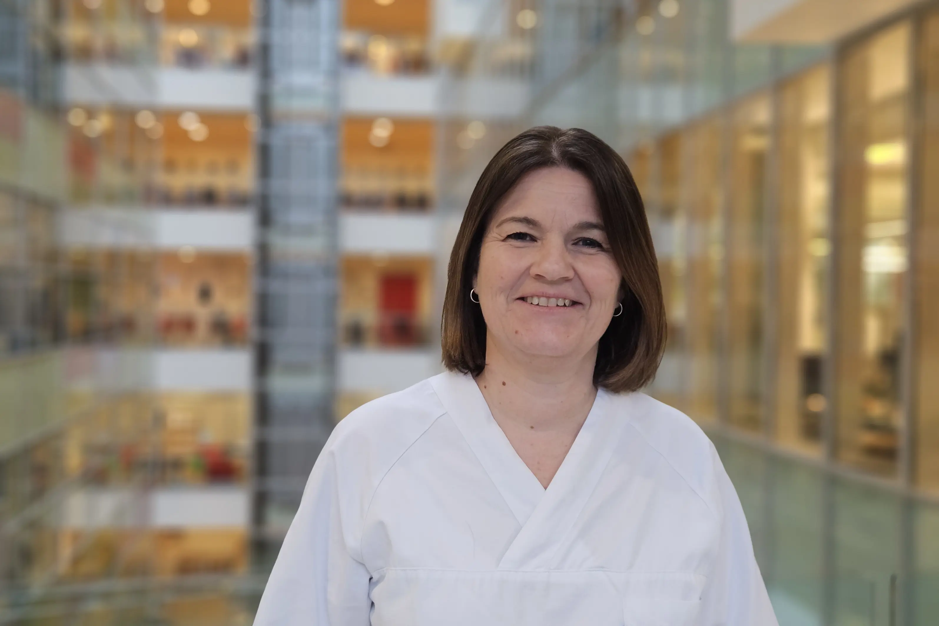 Kvinne med halvlangt mørkt hår smiler til kamera